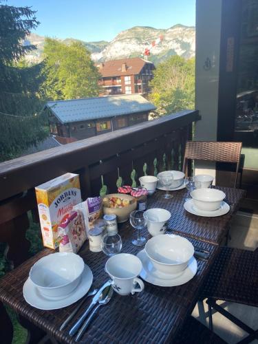 a table with plates and cups on a balcony at Loge des rêveurs in Les Carroz d'Araches