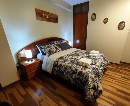 1 dormitorio con 1 cama y suelo de madera en El Balcón del Sol, en Cusco