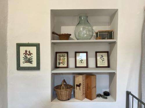a shelf with pictures and a vase on a wall at CasaVacanze Donna Manu in Cetona