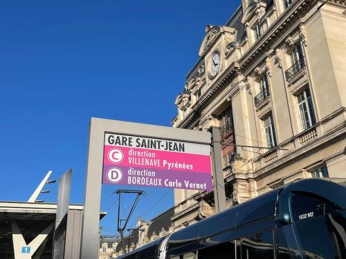 um sinal em frente a um edifício com uma torre de relógio em Appartement cozy à 100m de la gare Saint Jean em Bordeaux