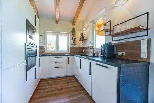 a kitchen with white cabinets and a black counter top at AusZeit Steiraland Penthouse 9 mit großen Balkon und Parkplatz in Leoben