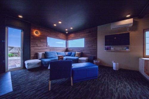 una gran sala de estar con un sofá azul y sillas en The OCEAN VISTA, en Shiraoi