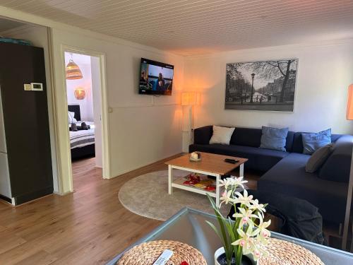 een woonkamer met een blauwe bank en een tafel bij BEEKBERGEN staying in the WOODS freestanding chalet WASMACHINE ALL COUNTRY TV CHANNELS EXPATS WELCOME in Beekbergen
