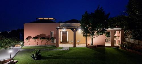 une maison avec une pelouse verte la nuit dans l'établissement Villa Magic Perla, à Gouviá