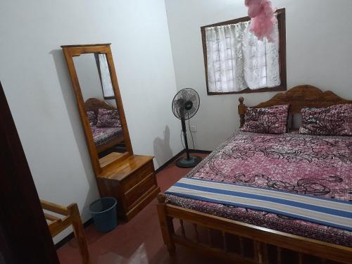 a bedroom with a bed and a mirror and a fan at Rosa Kusum Vacation Home Near Kudawa Beach In Kalpitiya in Kalpitiya