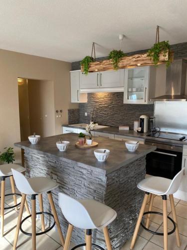 une cuisine avec des chaises blanches et un comptoir en pierre dans l'établissement Logis Gaïa, à Labenne