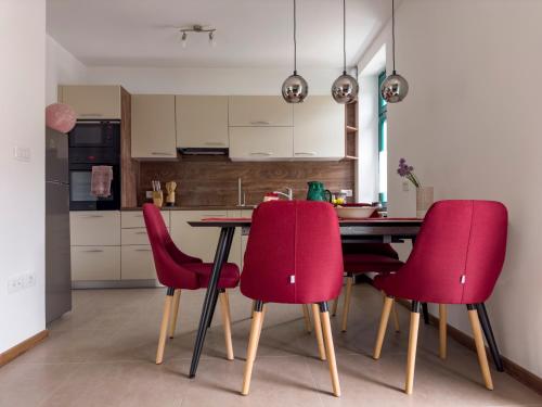 a kitchen with a table and four red chairs at Hiša Magnolija in Tolmin