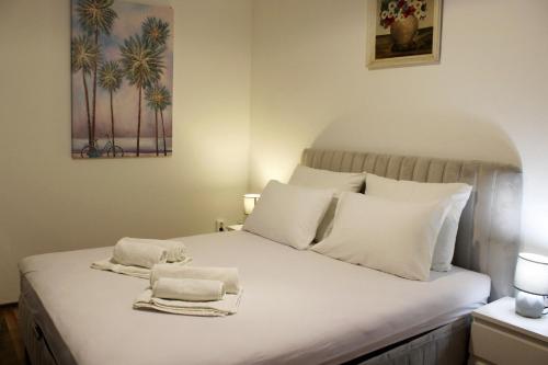 Una cama con almohadas blancas y toallas. en Bjelopera Rooms, en Zaton