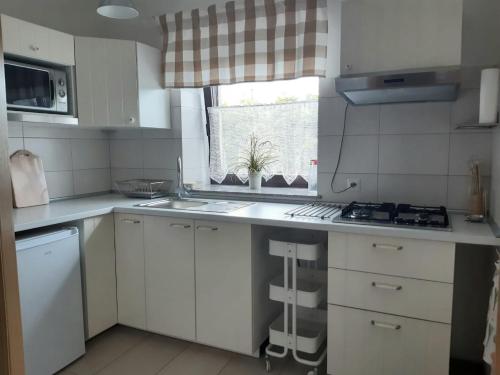 cocina con armarios blancos, fregadero y ventana en Apartamenty Rodzinne Pilica PARK, en Sulejów