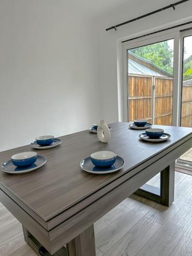 uma mesa de madeira com tigelas e pratos azuis em Comfortable Stay in 3 Bed House em Hither Green