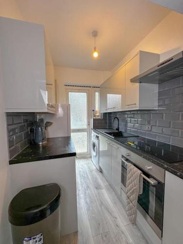 uma cozinha com electrodomésticos brancos e uma lata de lixo em Comfortable Stay in 3 Bed House em Hither Green