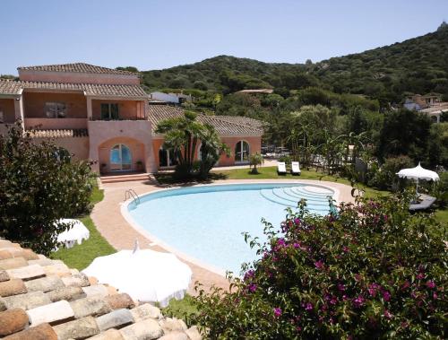 a villa with a swimming pool in front of a house at Hotel Cala Caterina in Villasimius