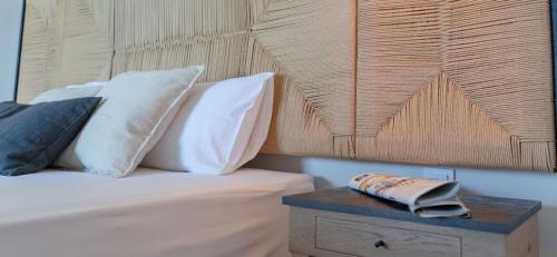 a bedroom with a bed with white pillows and a table at Αlissachne Suites in Limniónas
