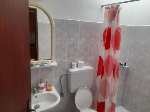 a bathroom with a red and white shower curtain and a toilet at Seva' s Studios in Livadia