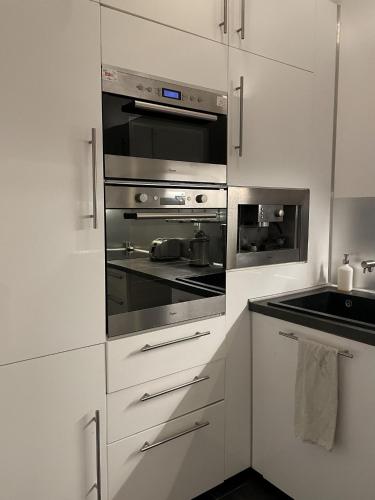 une cuisine avec des armoires blanches et des appareils en acier inoxydable dans l'établissement Spacieux T3 place Comédie gare Saint Roch, à Montpellier