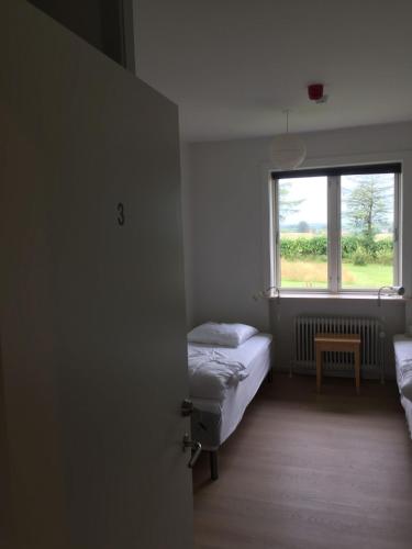 a small bedroom with a bed and a window at Aktivitetshuset Solhjem in Hjørring