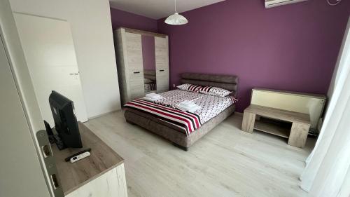 ein Schlafzimmer mit einem Bett und einer lila Wand in der Unterkunft Harmony Relax in Paraćin
