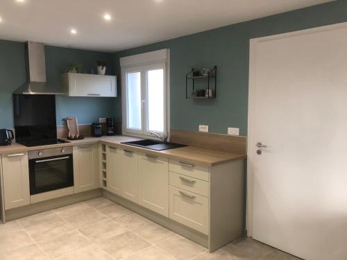 une cuisine avec des placards blancs et une porte blanche dans l'établissement Gîte 2 chambres, à Blaringhem