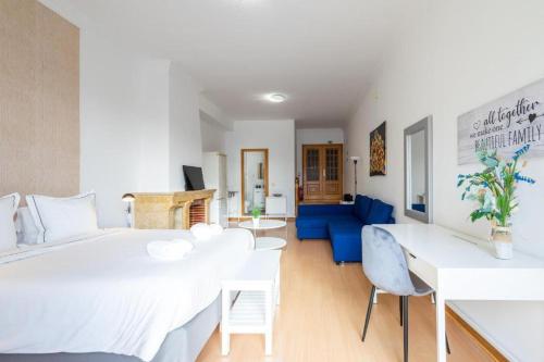 a bedroom with a white bed and a blue couch at Kubata Hill in Parede