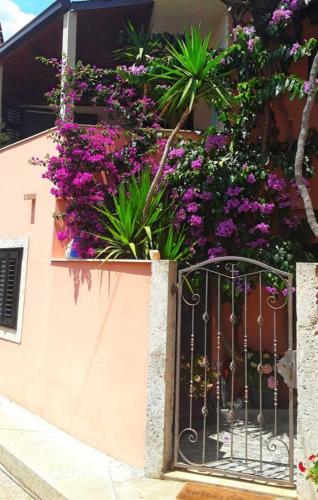 a gate with purple flowers on the side of a building at Bougainvillea--Apartment By The Sea in Ston