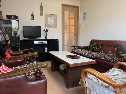 a living room with leather couches and a tv at PLATINUM kitaoji in Kyoto