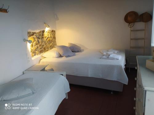 a bedroom with two beds with white sheets at Aiolos TRADITIONAL HOUSE IN ASTYPALAIA in Astypalaia