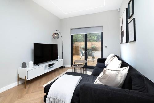 a living room with a black couch and a tv at Oak Tree Lodge in London