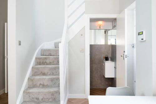 a hallway with a staircase with white walls and a white stair case at Oak Tree Lodge in London