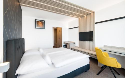 a bedroom with a white bed and a yellow chair at Hunguest Helios Hévíz in Hévíz