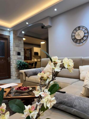 a living room with a couch and a clock on the wall at Ora House in Ayia Evfimia