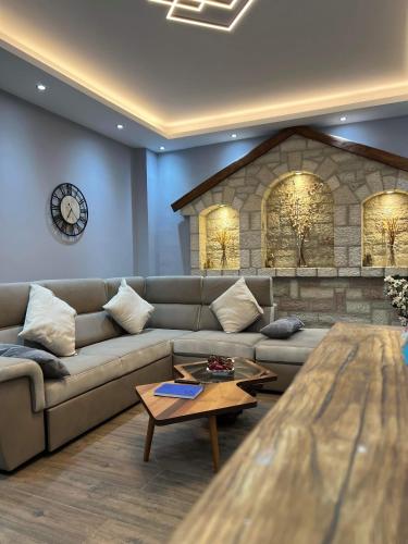 a living room with a couch and a clock on the wall at Ora House in Ayia Evfimia