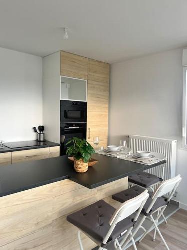 une cuisine avec un comptoir noir, une table et des chaises dans l'établissement Superbe appartement neuf dans résidence familiale aux portes de Paris avec parking, à Ivry-sur-Seine