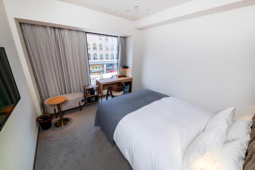 a bedroom with a bed and a desk and a window at The knot Sapporo - Vacation STAY 96374v in Sapporo