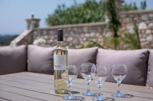 a bottle of wine sitting on a table with four wine glasses at Villa Aurora in Faliraki