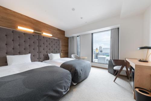 um quarto de hotel com duas camas e uma secretária e uma janela em The not Sapporo - Vacation STAY 96529v em Sapporo