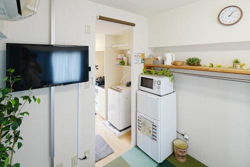 a kitchen with a tv on a white wall at Kameari 911 Budget Stay High Floor Near Station Mall Disney Access in Tokyo