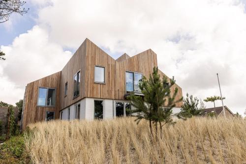 a house with wooden cladding in a field at VlieMare Appartementen De Kluut in Oost-Vlieland
