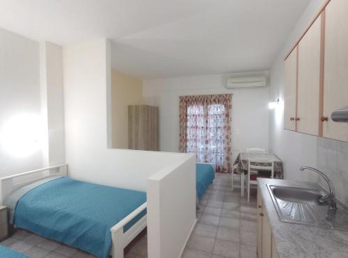 Dormitorio pequeño con cama y lavamanos en Flower Apartments, en Gouves