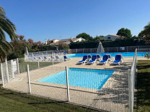 a fence with chairs and a swimming pool at Les Amareyeurs - Ile d'Oléron - Maison classée 3 étoiles avec piscine - Clim - Vélos in Le Château-dʼOléron