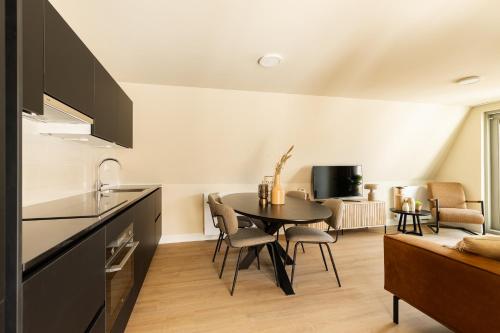 a kitchen and dining room with a table and chairs at VlieMare Appartementen De Kluut in Oost-Vlieland