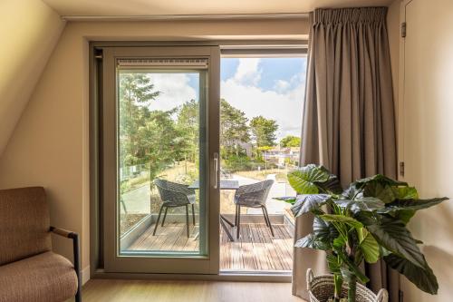 a sliding glass door leading to a patio with a table and chairs at VlieMare Appartementen De Kluut in Oost-Vlieland