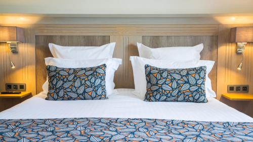 a bedroom with a bed with two pillows at Hotel Le Perigord in La Roque-Gageac