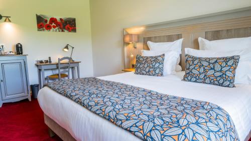 a hotel room with a large bed and a desk at Hotel Le Perigord in La Roque-Gageac