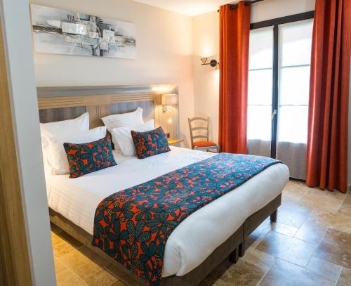 a bedroom with a large bed with red curtains at Hotel Le Perigord in La Roque-Gageac