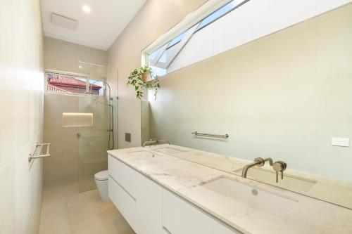 uma casa de banho com um lavatório, um WC e uma janela. em Eastern Beach Retreat em Geelong