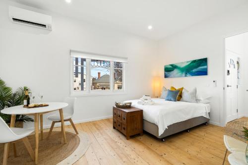 a white bedroom with a bed and a table at Eastern Beach Retreat in Geelong