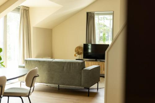 a living room with a couch and a tv at VlieMare Appartementen De Kluut in Oost-Vlieland