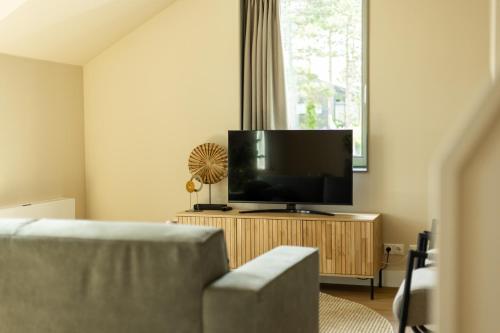 a living room with a couch and a flat screen tv at VlieMare Appartementen De Kluut in Oost-Vlieland