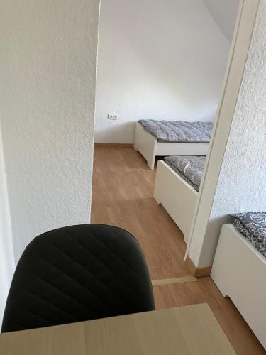 a room with two beds and a black chair at Günstiges Apartment Gelsenkirchen Schalke in Gelsenkirchen