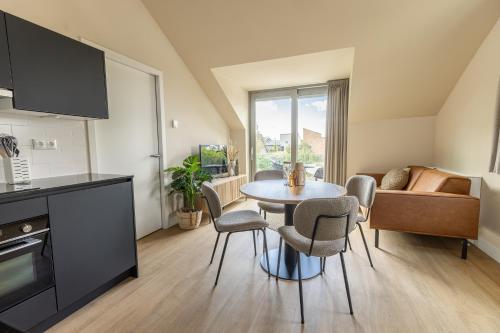a kitchen and living room with a table and chairs at VlieMare Appartementen De Kluut in Oost-Vlieland